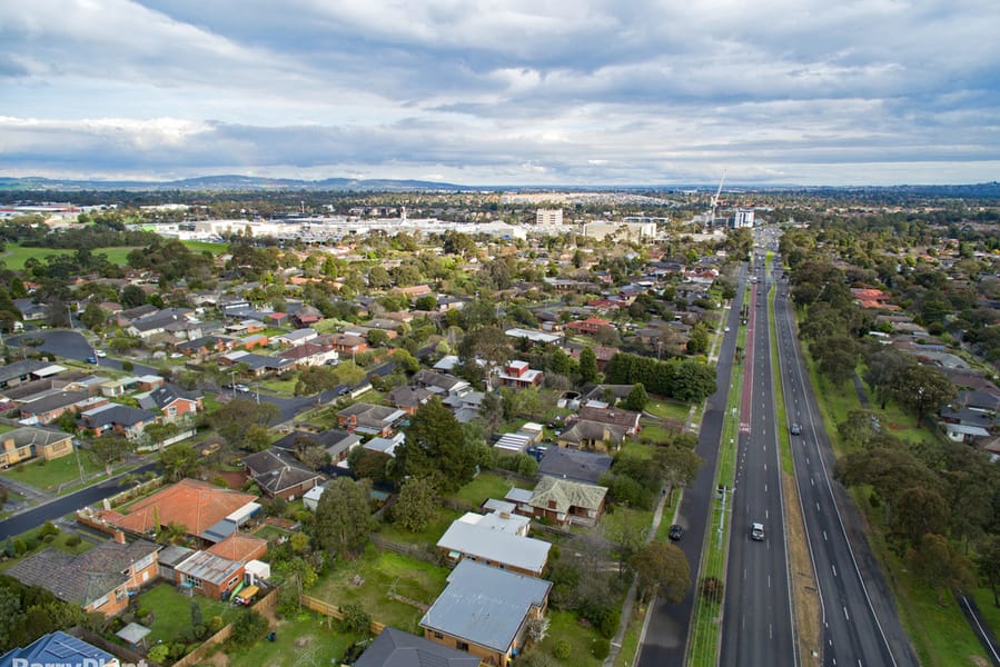 Aerial view over Wantirna's houses and gardens beside a divided road, with the hills on the horizon